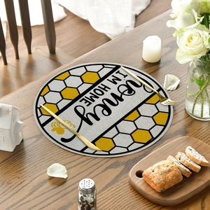 Detailed close-up of a honeycomb linen place mat with Honey I'm Home slogan on a wood table