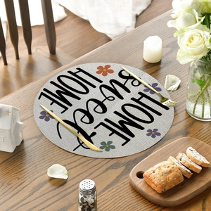 Detail of round linen placemat with Home Sweet Home text and floral pattern on wood table