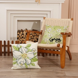 Floral spring cushion covers with white flower print and Spring text on rustic chair