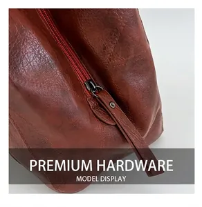 Close-up of high-quality metal zipper on vintage red-brown leather tote with neat stitching