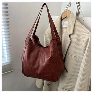 Close-up of a terracotta vintage leather tote bag with patchwork stitching details