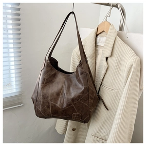 Close-up of vintage patchwork design on large brown leather tote bag hanging on a hook