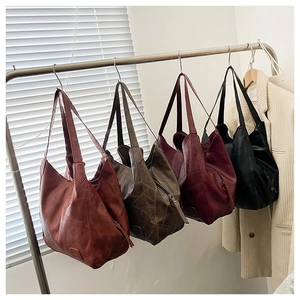 Detail view of four vintage leather tote bags in various colors on a display rack