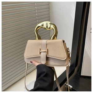 Detail view of beige crossbody bag with gold metallic handle and canvas texture