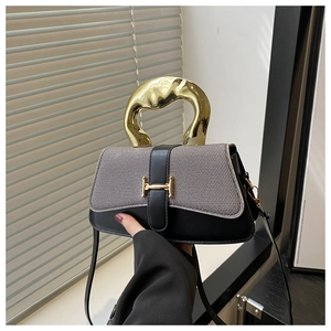 Detail of tweed and black leather handbag featuring a unique gold metal handle and H-buckle