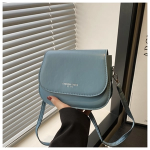Detail of light blue square crossbody bag with silver Fashion Trend logo text
