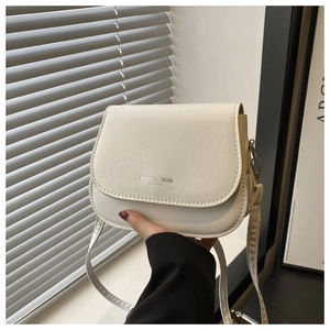 Detail showing cream saddle bag with contrast stitching and golden hardware