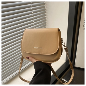 Close-up of matte khaki saddle bag with silver FASHION TREND EST 1990 embossed logo