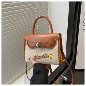 Dettaglio della borsa in tela a contrasto con finiture in pelle e ricamo timeto