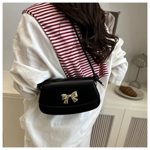 Détail du sac bandoulière noir avec une boucle décorative en nœud doré