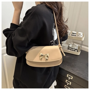 Détail d'un sac bandoulière beige chic avec boucle nœud dorée et fines lanières en cuir