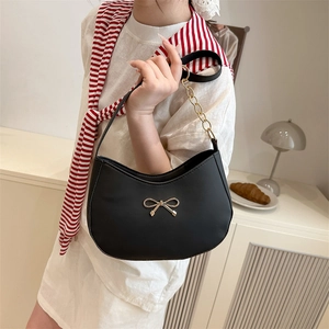 Chic black leather underarm bag with a golden bow accent and chain shoulder strap
