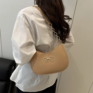 Elegant beige crescent shoulder bag with golden bow hardware and leather chain strap