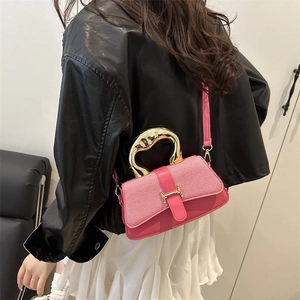 Pink crossbody bag with large golden handle and H-buckle shown on model in street style