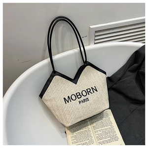 Détail de la broderie MOBORN PARIS sur un sac cabas en paille avec anses en cuir noir