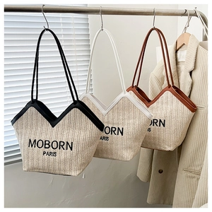 Tres bolsos tote de paja tejida en negro blanco y marrón colgados en un perchero