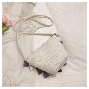 Detail of woven white shoulder bag featuring colorful tassels and boho rope strap style