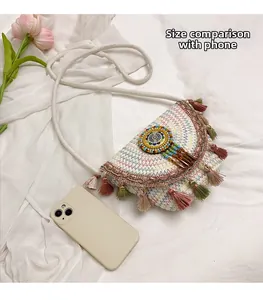 Detail of woven half-moon crossbody bag with colorful fringe and size comparison to a phone