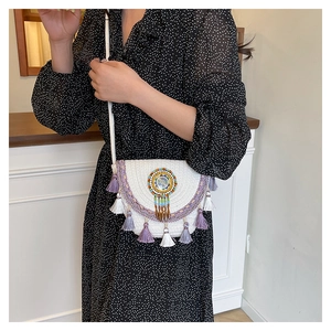 Detail of white woven saddle bag with ethnic beaded pattern and purple fringe tassels