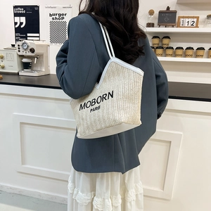 Bolso tote de paja beige con correas de cuero blanco y letras negras bordadas a la moda