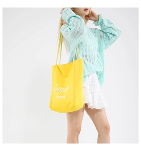 Yellow canvas tote bag detail showing beyou and merci text with a stylish outfit