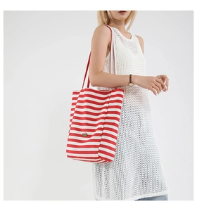 Model wearing a red and white striped canvas tote bag with contrast shoulder straps
