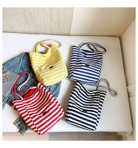 Detail showing four colorful striped canvas tote bags with elegant metal logo and long handles