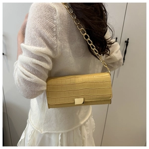 Détail de la texture crocodile beige et de la bandoulière en chaîne dorée du sac
