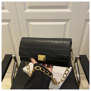 Detailed view of black croc-embossed small square bag with chunky gold chain and lock