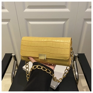 Detail of yellow crocodile embossed leather texture with golden chain on shoulder bag