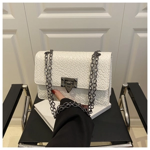 Close-up of white woven leather texture with gunmetal chain strap and metal lock buckle