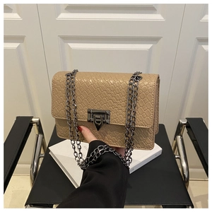 Close-up of stone pattern crossbody bag with gunmetal chain and triangle clasp detail