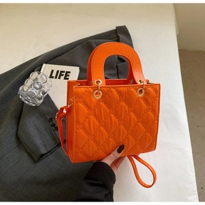 Close-up of the orange quilted diamond pattern and glossy PU leather on the handbag