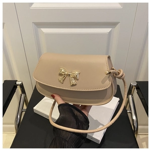 Détail d'un sac bandoulière beige élégant avec un nœud métallique doré en 3D