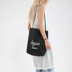 Minimalist black canvas tote bag with white merci print and long dual rope handles