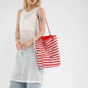 Red and white striped canvas tote bag with long straps shown on model in studio