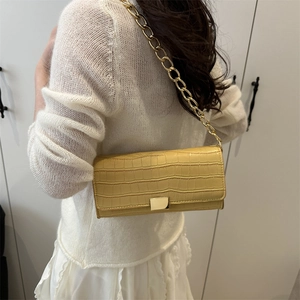 Sac à bandoulière jaune motif crocodile avec chaîne dorée porté par un mannequin chez soi