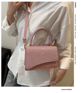 Close-up of pink crossbody bag with sparkling glitter handle and gold miss.mini logo