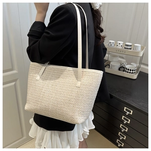 Detailed macro view of beige woven straw tote bag texture with slim shoulder straps