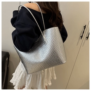 Silver woven tote bag shown on model's shoulder highlighting large capacity and metallic texture