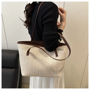 Detail of a large woven tote bag in cream with dark brown straps worn by a model