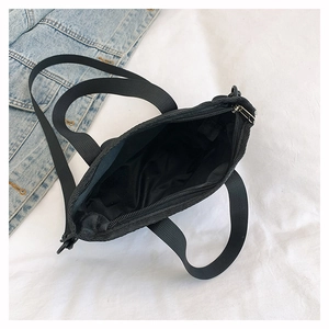Black corduroy top handle bag interior with zipper closure and adjustable shoulder strap