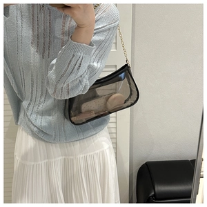 Detail of black translucent shoulder bag with gold chain showing makeup storage