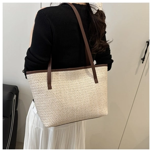 Close-up of beige woven straw tote bag with brown leather shoulder straps for summer