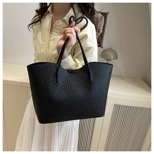 Close-up of a black woven leather tote bag with elegant handles and fine grid texture