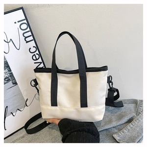 Minimalist canvas tote bag featuring contrast black straps and adjustable shoulder strap