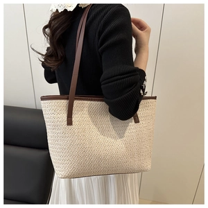 Detailed close-up of woven straw tote bag texture with brown leather straps for summer