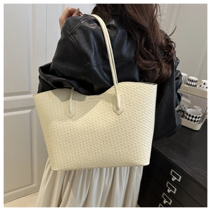 Detail view of the cream woven tote bag featuring textured pattern and long shoulder straps