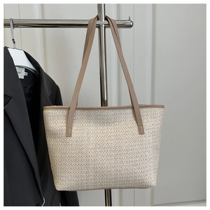 Detail of hand-woven straw tote bag with premium faux leather straps and stitching