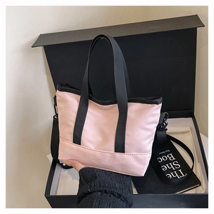 Close-up of pink mini tote bag with black straps inside a gift box for city commuting